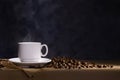 Coffee cup with saucer and scattered coffee beans on dark background Royalty Free Stock Photo