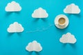 Coffee cup in shape of balloon with clouds on blue paper background