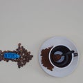 Coffee cup, spoon, and coffee bean arrow and blue boat on it with copy space on beige background. Minimal flat lay scene