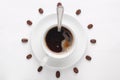 Coffee cup with spoon on saucer and coffee beans against white background forming clock dial viewed from top Royalty Free Stock Photo