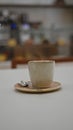 Coffee cup with spoon on saucer placed on table in cozy indoor restaurant setting with blurred background Royalty Free Stock Photo