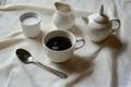 coffee cup with a spoon, sugar bowl, and creamer on side