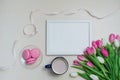 Coffee cup, spring tulip flowers and pink macarons on pastel table top view. Greeting for Womans or Mothers Day Royalty Free Stock Photo