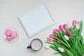 Coffee cup, spring tulip flowers and pink macarons on pastel table top view. Greeting for Womans or Mothers Day Royalty Free Stock Photo