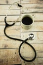 Coffee cup and stethoscope on wooden background.