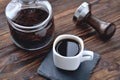 Coffee in a cup on a stone stand, glass jar with coffee beans and coffee tamper, wooden natural background Royalty Free Stock Photo