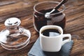 Coffee in a cup on a stone stand, glass jar with coffee beans and a vintage spoon, wooden natural background Royalty Free Stock Photo