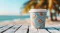 coffee cup with a tropical leaf pattern, placed on a wooden table by the beach with palm trees Royalty Free Stock Photo
