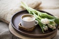 Coffee cup with tulips bouquet in wooden plate, home cozy interior details Royalty Free Stock Photo