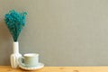 Coffee cup with vase of blue baby`s breath gypsophila dry flowers on wooden table Royalty Free Stock Photo