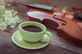 Coffee cup and violin on wooden table, filtered image