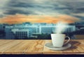 Coffee cup white placed on wooden table with smoke, With cityscape sunset background,refreshing and relaxing with warm drinks Royalty Free Stock Photo