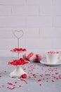 Coffee cup, white two tier serving tray full of multicolor sweet sprinkles sugar candy hearts and packing Valentine`s Day gifts Royalty Free Stock Photo