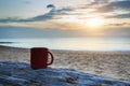 Coffee cup on wood log at sunset or sunrise beach Royalty Free Stock Photo