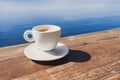 Coffee cup on a wood table over blue sky and sea background. Summer holiday concept Royalty Free Stock Photo