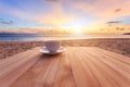 Coffee cup on wood table at sunset or sunrise beach