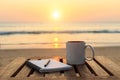 Coffee cup on wood table at sunset or sunrise beach Royalty Free Stock Photo