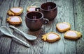 Coffee cups, strawberry cream cookies and white spoons on a wooden table