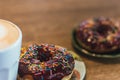 Coffee with a drawn heart and milk on a wooden table in a coffee shop. two chocolate donuts with scattering on the table next to Royalty Free Stock Photo