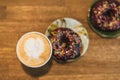 Coffee with a drawn heart and milk on a wooden table in a coffee shop. two chocolate donuts with scattering on the table next to Royalty Free Stock Photo