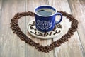 Coffee drink in a mug and black coffee beans in a heart shape Royalty Free Stock Photo