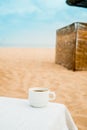 Coffee espresso cup with ocean , beach and seascape. Blue sky, white sand, woven zonik, wooden beach chair. Sea Royalty Free Stock Photo