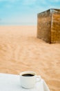 coffee espresso cup with ocean , beach and seascape. Blue sky, white sand, woven zonik, wooden beach chair. Sea vacations. The Royalty Free Stock Photo
