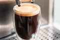 Coffee espresso streaming from coffee machine and pouring into glass Royalty Free Stock Photo