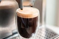 Coffee espresso streaming from coffee machine and pouring into glass Royalty Free Stock Photo