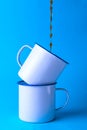 Coffee falling on two white metal cups Royalty Free Stock Photo