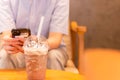 Coffee Frappuccino Blended with paper straw and people using cell phone in background.