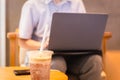 Coffee Frappuccino Blended with paper straw and woman using laptop in background.