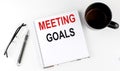 Coffee,glasses,pen and notebook written with MEETING GOALS on white background Royalty Free Stock Photo