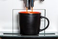 Coffee going out from a coffee machine in black mug. Royalty Free Stock Photo