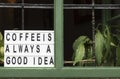 Coffee is always a good idea signboard at a window of a vintage cafe full of plants, script home decor