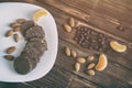 Coffee grains, almond nuts, tangerine slices and chocolate sausage pastry on a wooden surface. Vintage processing