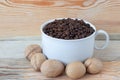 Coffee grains in a white cup and nuts