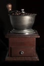 Walnut coffee grinder full of coffee beans on black background
