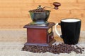 Coffee grinder full of roasted coffee beans and black mug