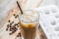 Coffee ice cubes and beans with latte on wooden desk background Royalty Free Stock Photo