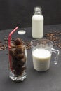 Coffee ice cubes in a glass with a red straw, milk in measuring cup, milk