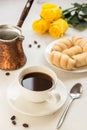 Coffee, jezva and sweet bakery on a white table, yellow roses on