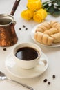 Coffee, jezva and sweet bakery on a white table, yellow roses on