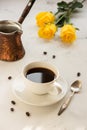 Coffee and jezva on a white table, yellow roses on a background