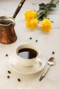 Coffee and jezva on a white table, yellow roses on a background