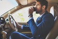 Coffee keeps him going. Shot of a cheerful young businessman driving in his car to work while sitting in traffic and Royalty Free Stock Photo