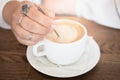 Coffee late in white cup and female hand with spoon, close up. Good morning concept idea Royalty Free Stock Photo