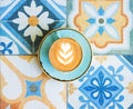 Coffee with latte art in blue cup on colorful tile background. Royalty Free Stock Photo