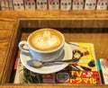 Coffee Latte with Latte Art on glass table with Manga comics below Royalty Free Stock Photo