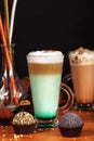 Coffee latte macchiato with mint syrup and whipped cream, in high transparent glasses with cakes, on a dark background Royalty Free Stock Photo